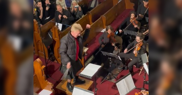 Man in a kilt conducting an orchestra in a silly way.