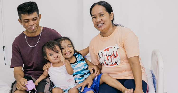 Mom and dad smiling with their 2 and 6 year old's who both have clefts.