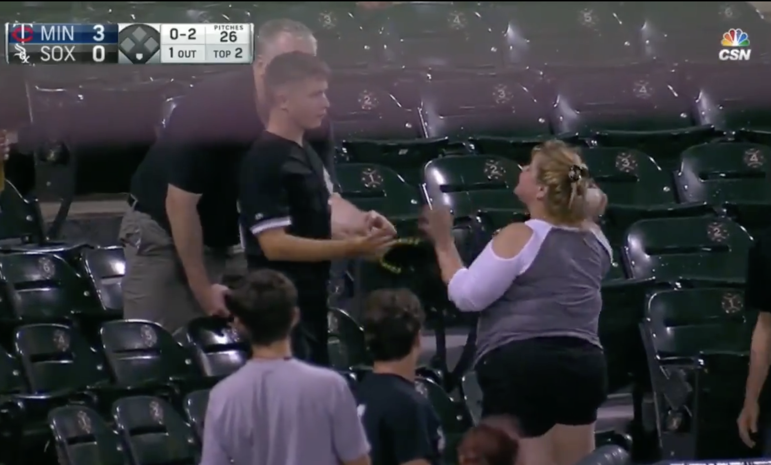 woman talking to a teen after she grabbed a baseball from his hand at a baseball game. 
