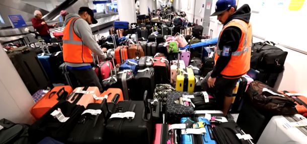 Two men are searching through luggage in an airport.