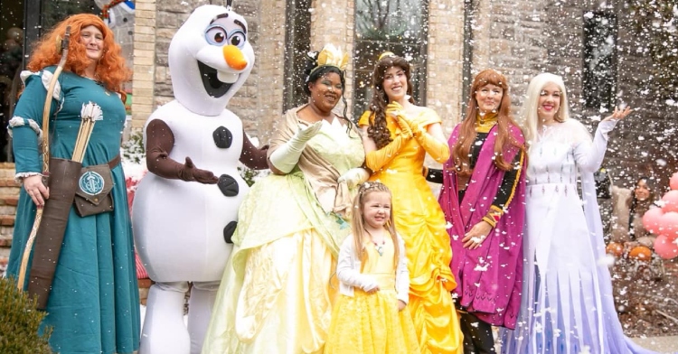 Adalyn smiles with Disney princesses Anna, Elsa, Belle, Tiana, Mereda, and Olaf.