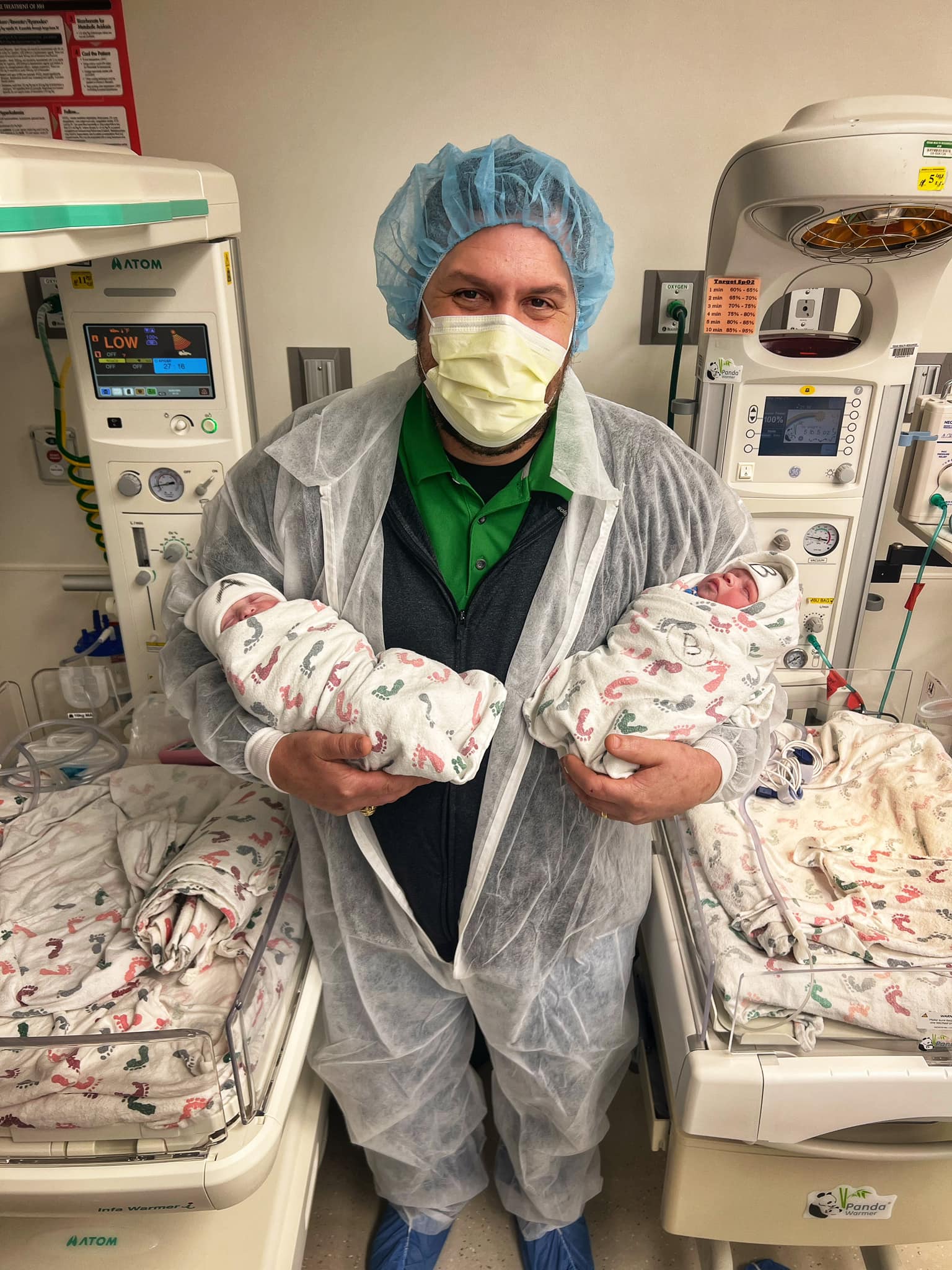 Cliff Scott wearing a mask and holding his newborn daughters in the hospital