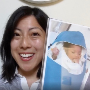 Grace Hsia Haberl holding up a photo of an infant wearing a Warmilu blanket.