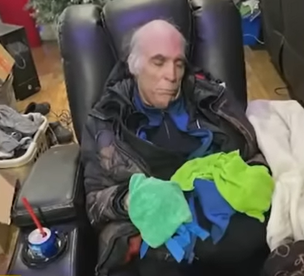 Joe White sleeping in a recliner while he is all bundled up to keep him warm.