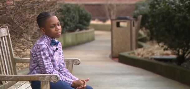 A 9-year-old boy named Kayden is sitting on a park bench.