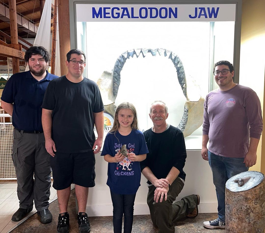 Molly Sampson shows off her megalodon tooth to scientists at Calvert Marine Museum.