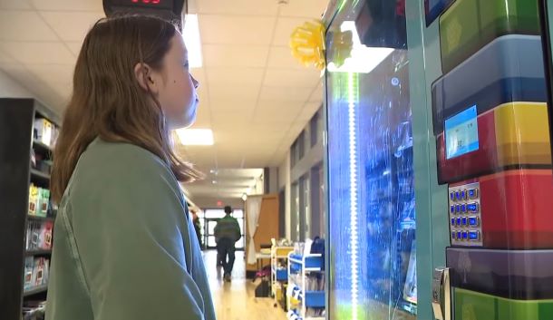 A student is looking at book selections in a vending machine.