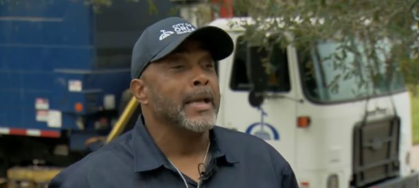 A Tony Parker wearing a hat and talking about a memory, standing in front of his garbage truck