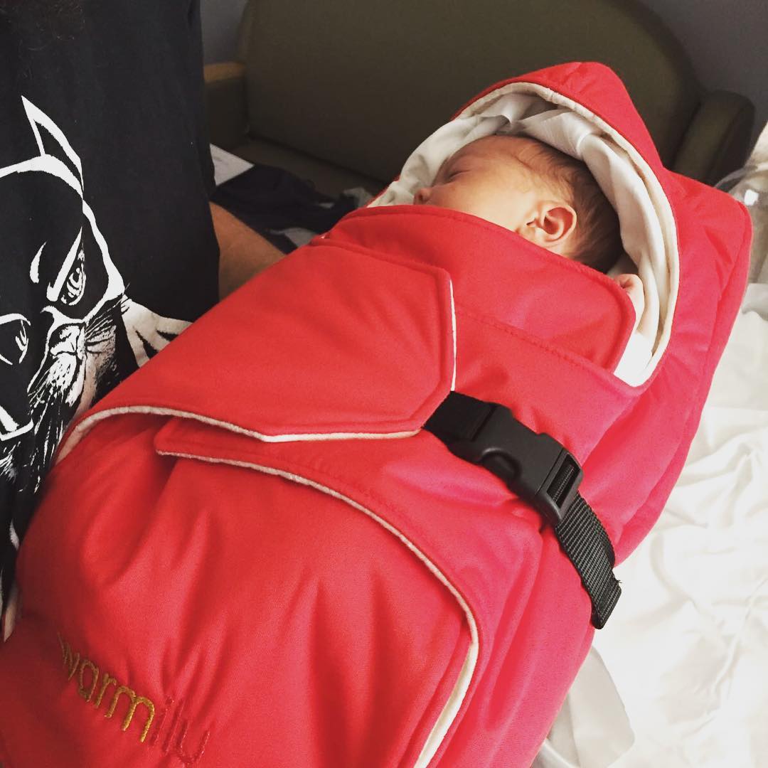 infant wearing a red Warmilu blanket