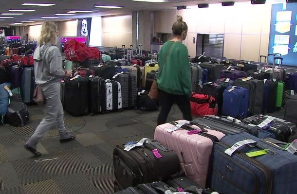 Travelers walking through an aisle of luggage.