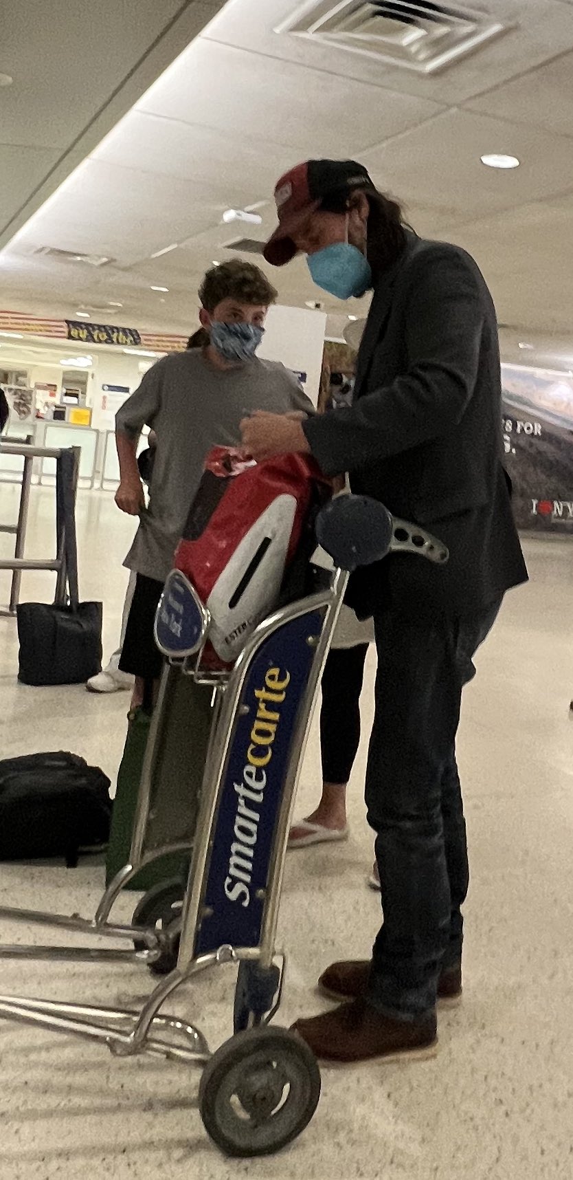boy asking Keanu Reeves questions at airport.