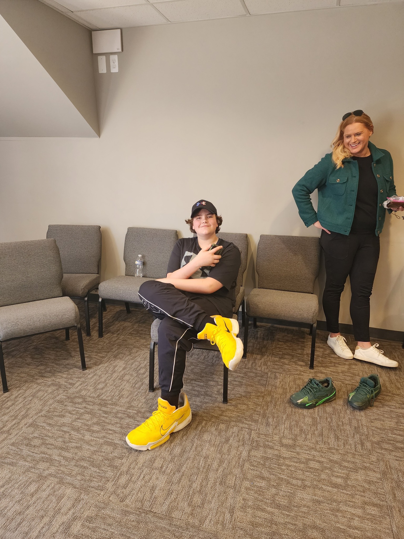 Eric Kilburn Jr wearing yellow sneakers with mom smiling behind him.