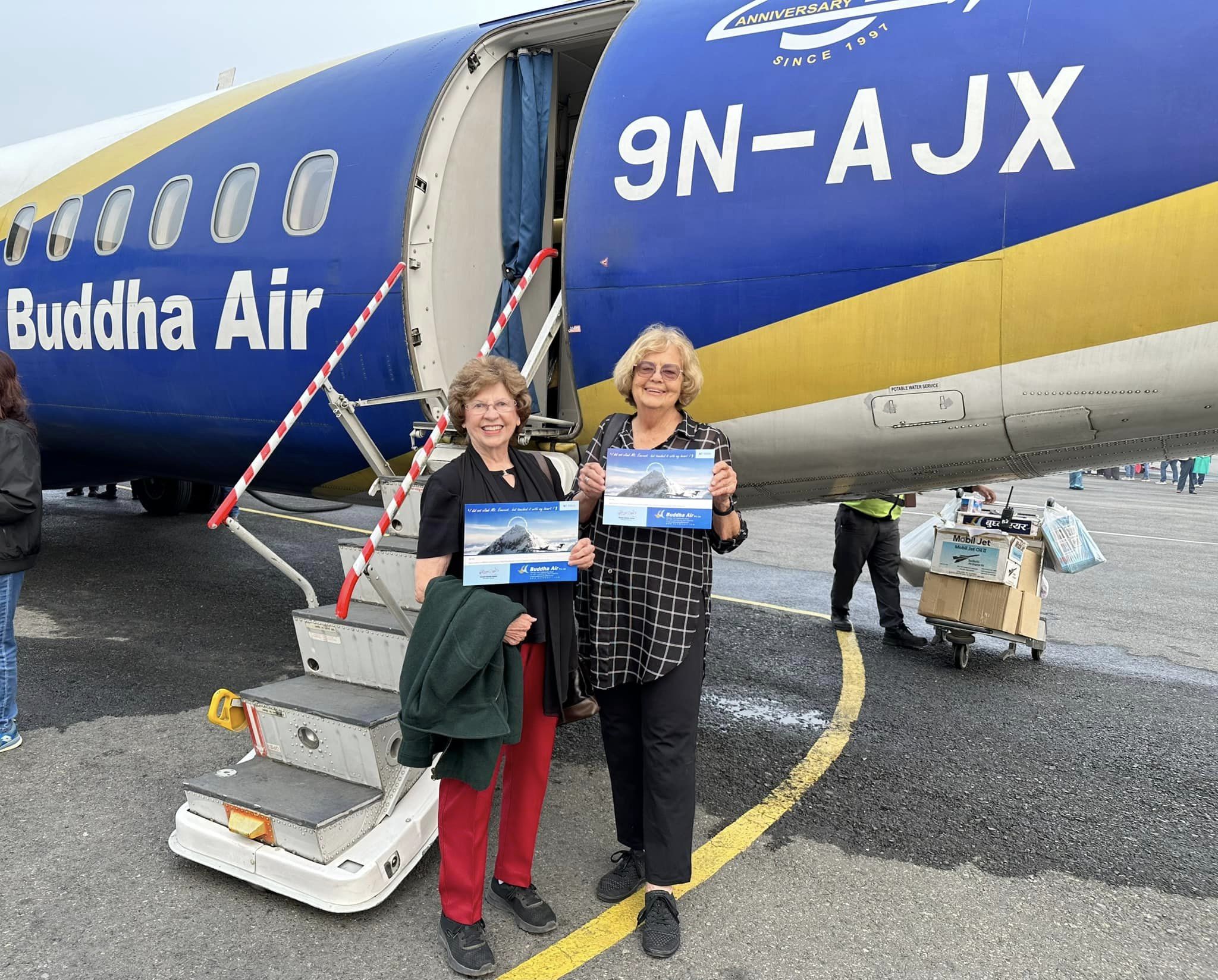 Sandy Hazelip and Ellie Hamby holding certificates stating they flew over Mt. Everest in a plane.