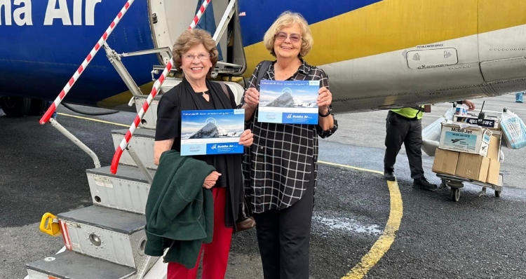 Sandy Hazelip and Ellie Hamby holding certificates stating they flew over Mt. Everest in a plane.