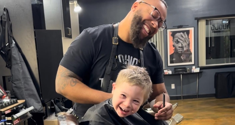 Vernon Jackson laughs while cutting Ellison's hair.