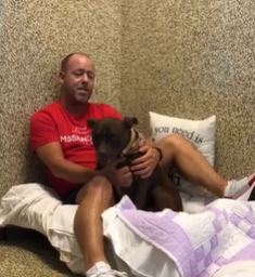 Scott Poore sitting on a makeshift bed with Queen the dog