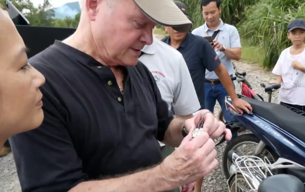 Jim Webb examines dog tags found in Vietnam.