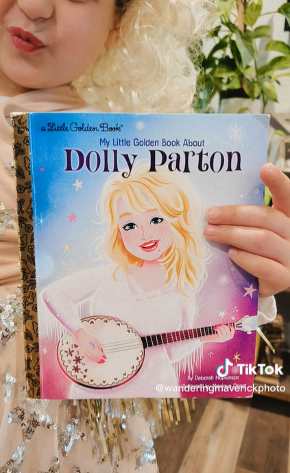 Stella Ruby holding up a Little Golden Book about Dolly Parton.