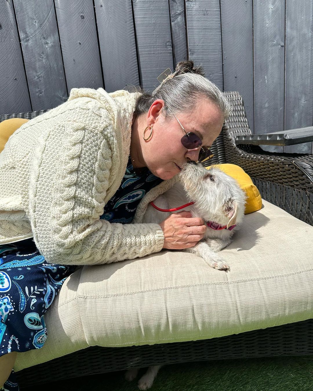 Suzette Hall kissing small white dog on face.