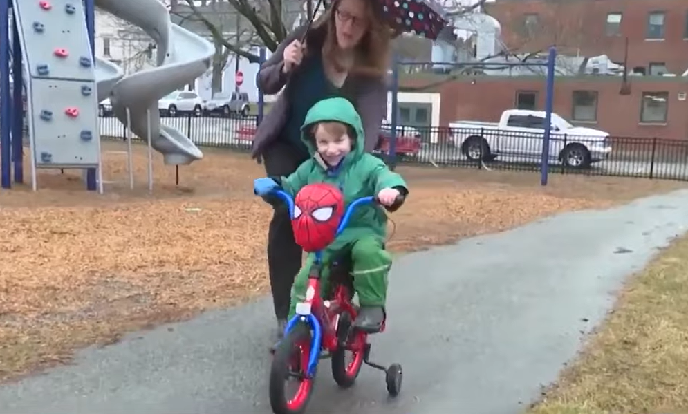 Liz Fuller-Wright helps her son Will ride his Spider-Man bike on the sidewalk.