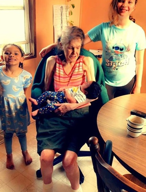 Samantha's grandmother holding an infant with two older children by her side.