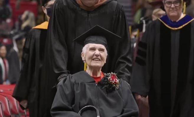 Joyce in a cap and gown being pushed in a wheelchair at her commencement