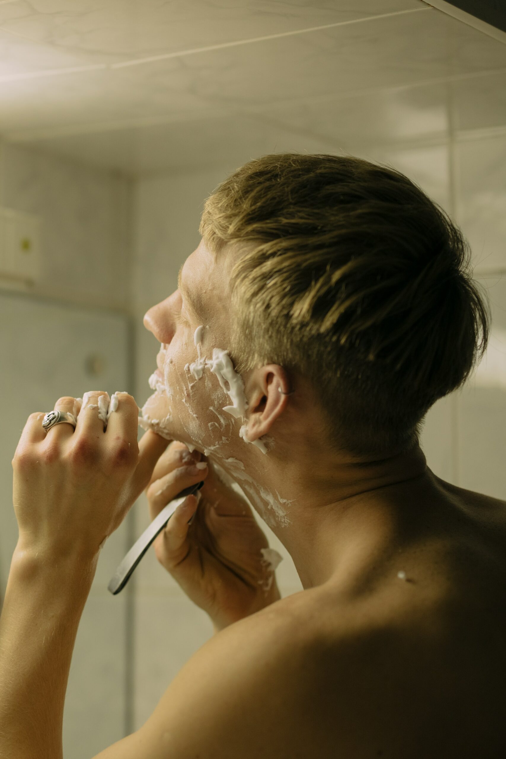 man shaving his face in mirror