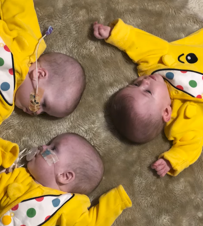 triplets lying with heads together in circle.