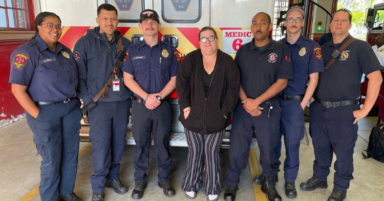 A grateful wife poses with the firefighters who saved her husband's life.
