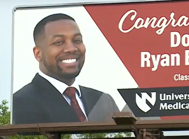 A billboard displays a photo of med school graduate Dr. Ryan Boyland.