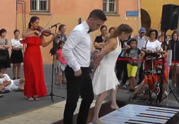 Leo Moreno and Silvia Zotto dancing on giant piano keys on the ground