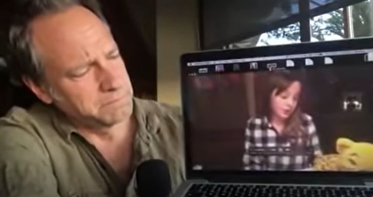 Mike Rowe, amused, watching a video of Charlotte McCourt