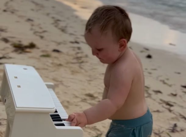 Baby Gavriil Scherbenko plays a toy keyboard on the beach. 