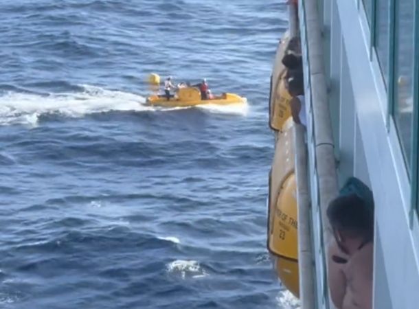 A boat searches for the overboard passenger next to the cruise ship.