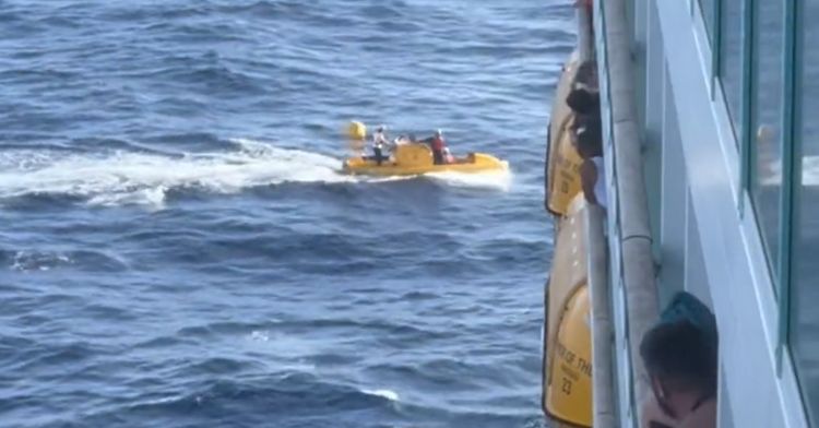 A boat searches for the overboard passenger next to the cruise ship.