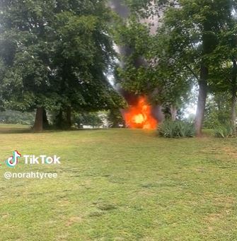 a screenshot from a tiktok showing a car burning up in the background.
