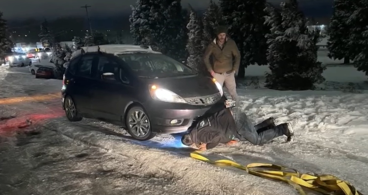 Jon Gilbert attaching tow rope to stranger's car during ice storm.