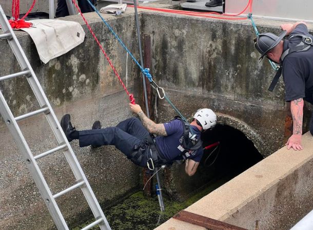 A firefighter is lowered into the water tank to rescue the baby deer.