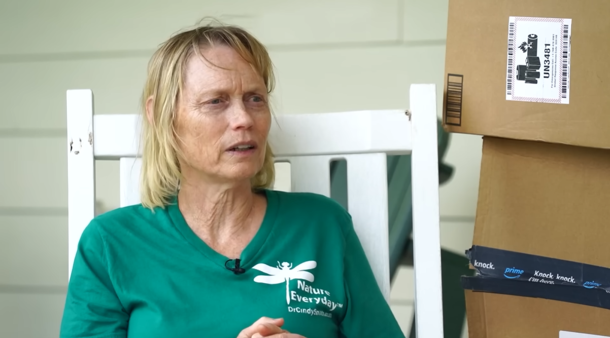 Cindy Smith talks as she sits on her front porch swing next to a stack of Amazon boxes.