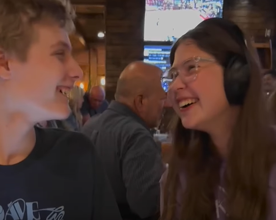 Two friends are shown laughing in a restaurant