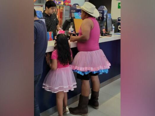 A father and daughter stand at the concessions counter wearing fully pink outfits.
