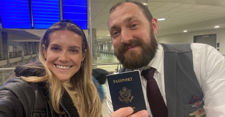 A woman smiles as a Delta Air Lines employee holds up a passport.