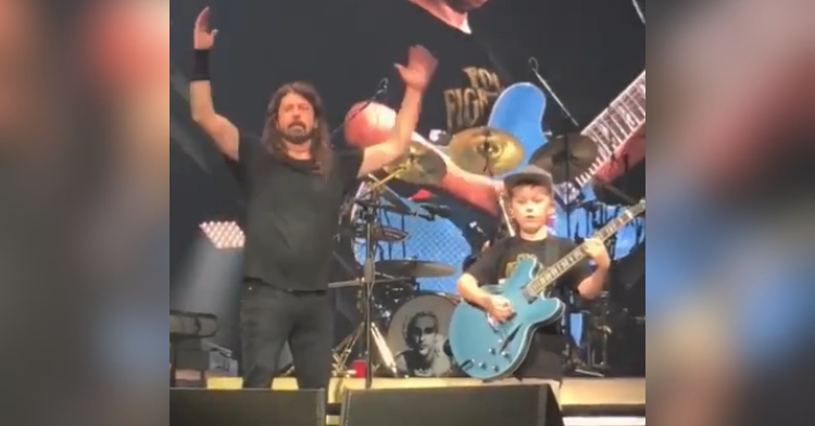 David Grohl throws his hands in the air in amazement as the 10-year-old fan he invited on stage plays the guitar perfectly.