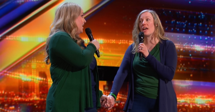 Holly and Kim hold hands as they look at each other and sing on the "America's Got Talent" stage.