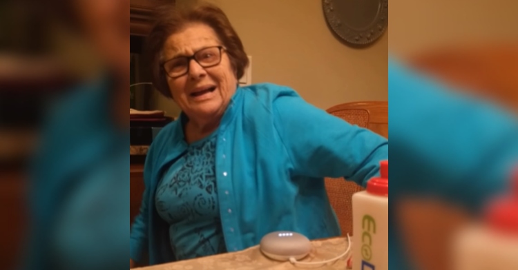 85-year-old Italian grandmother looks shocked as she laughs. A Google Home device sits at the table in front of her.