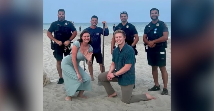 The Tennessee couple smile and pose after getting engaged. The man is on one knee and the woman happily shows off the engagement ring on her hand. The Myrtle Beach Police Department officer and another man pose with them.