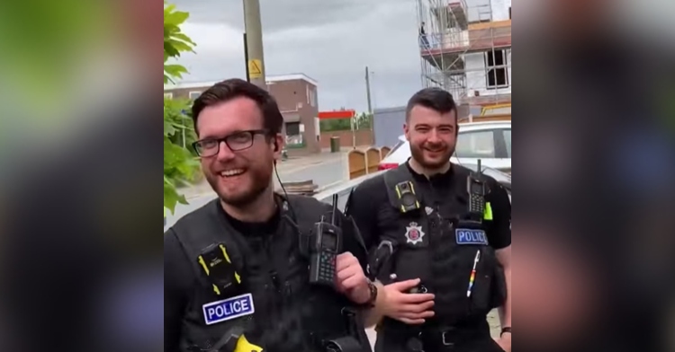 Two Essex Police Officers smile and laugh outside of Steve Wood's house.