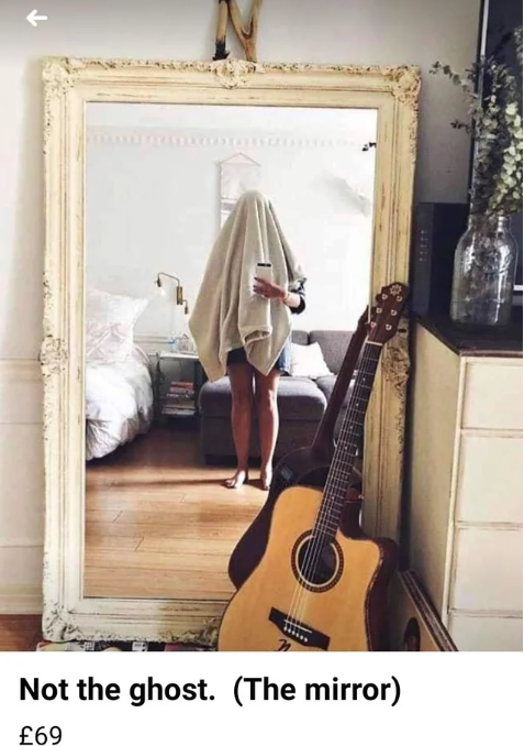 Someone is taking a photo of a mirror, fully showing themselves taking the photo with a sheet over their head. The mirror is for sell. The item for sell is captioned: Not the ghost. (The mirror) and is priced at 69 pounds.