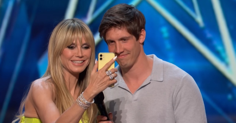Heidi Klum smiles as she holds "AGT" contestant Trent Toney's phone. They're both looking at the phone, FaceTiming his ex-wife, Faith.