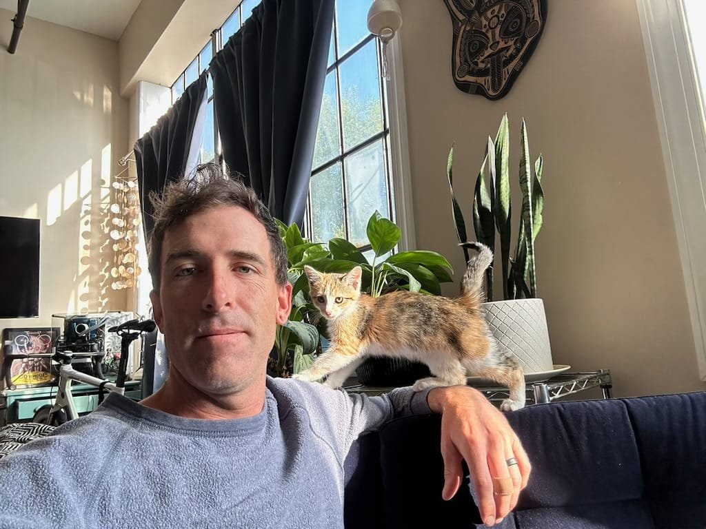 Officer Rugg at home with kitten crawling on his shoulder.